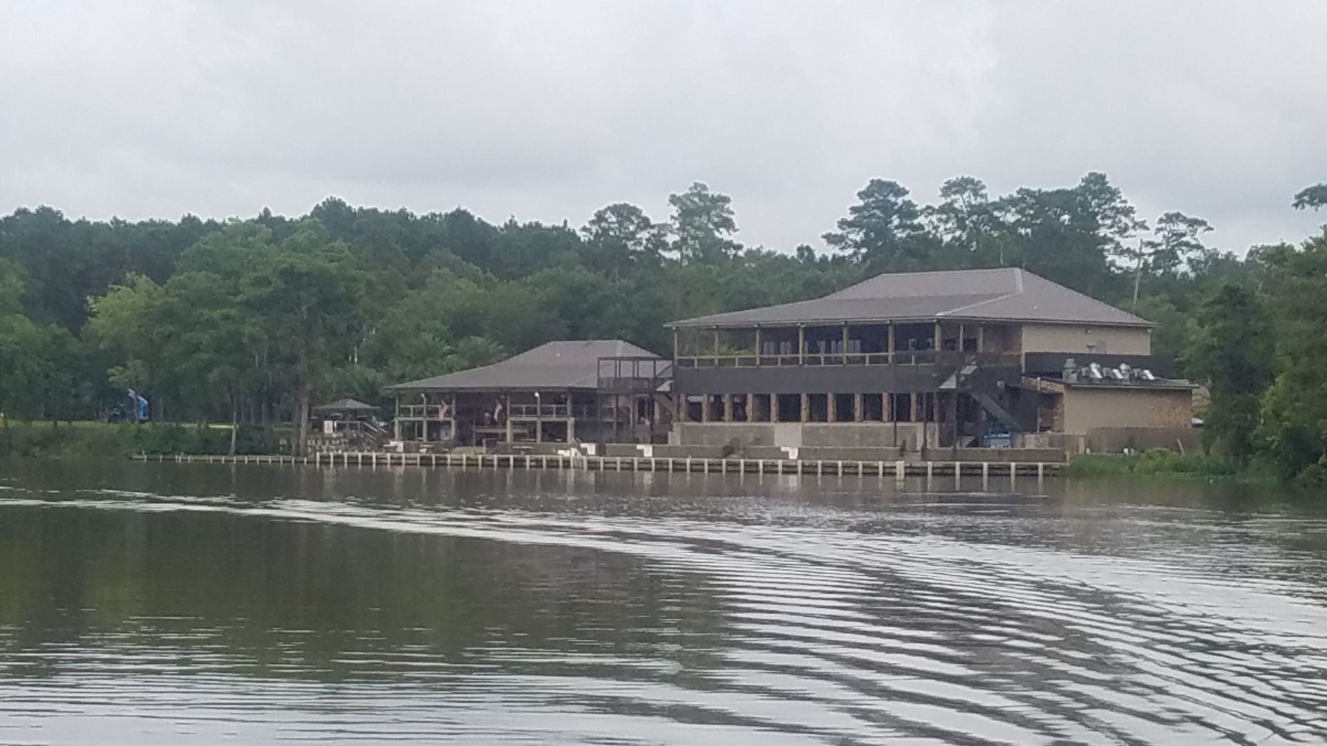 A large house is sitting on top of a lake surrounded by trees.