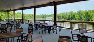 A patio with tables and chairs overlooking a lake