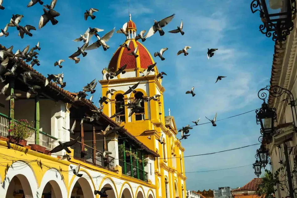 Iglesia colonial de Mompox con palomas volando, atractivo turístico cerca del Hotel Karakalí