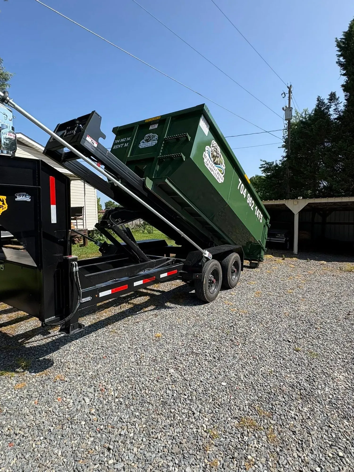 A dumpster is being pulled by a truck on a trailer.