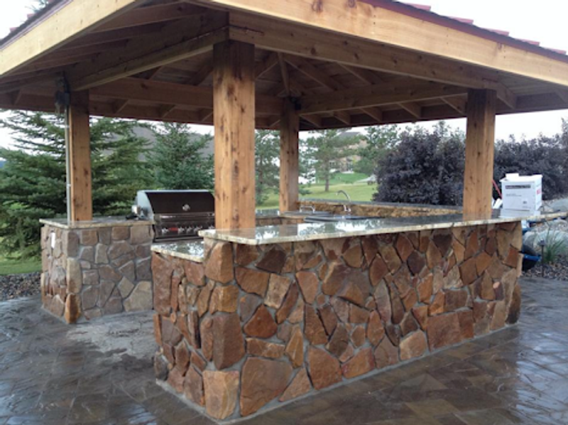 A wooden gazebo with a grill underneath it