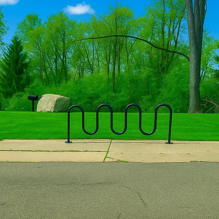 Black bicycle rack on a concrete path in a park with green grass and trees under a blue sky.