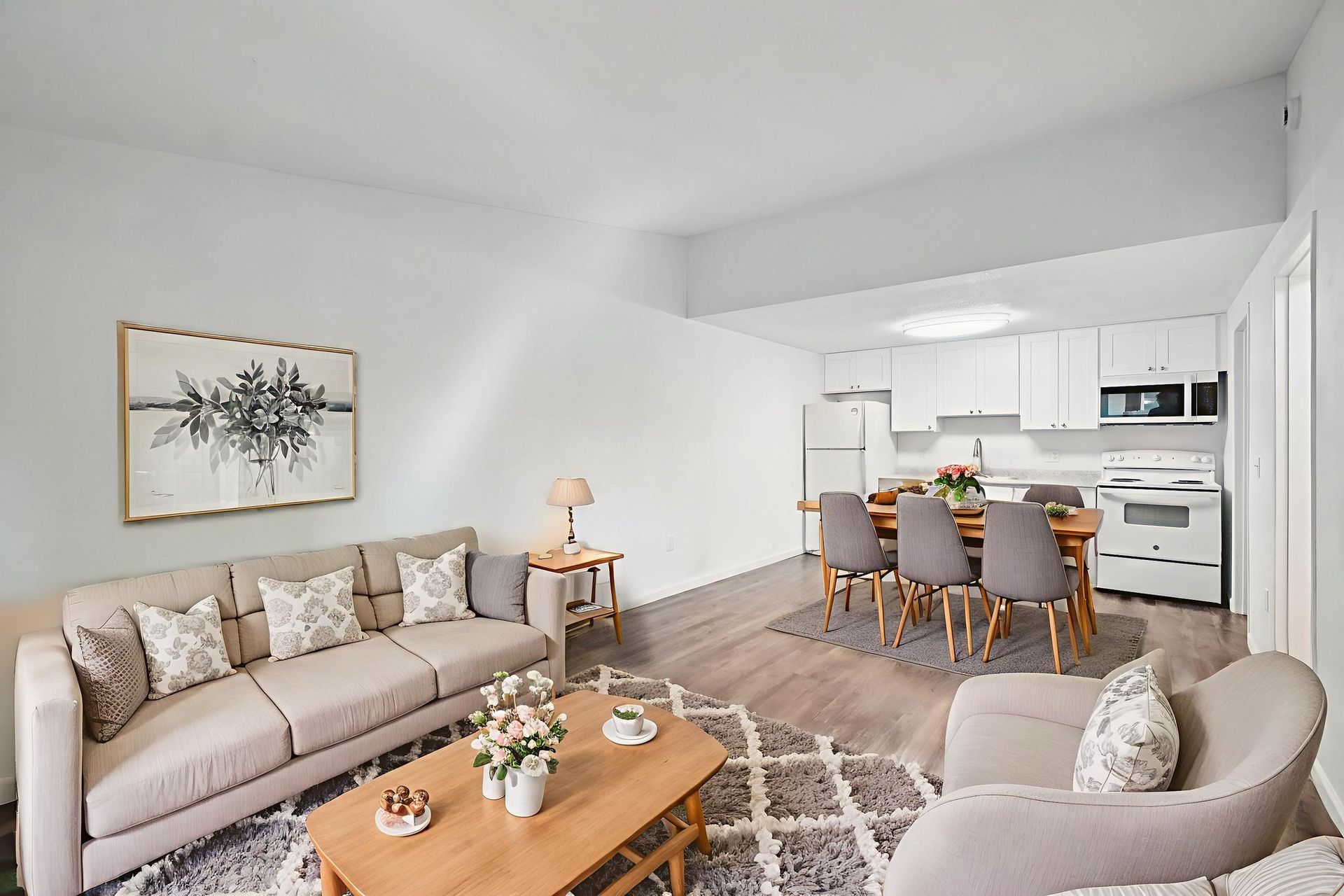 Living room with beige furniture, dining area, and white kitchen.