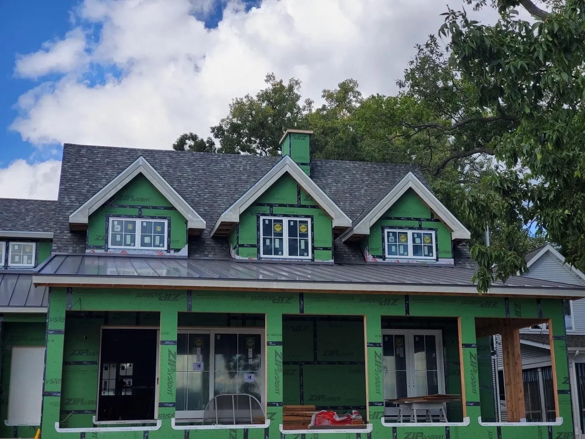 House under construction with windows, and three dormers with gray roof.