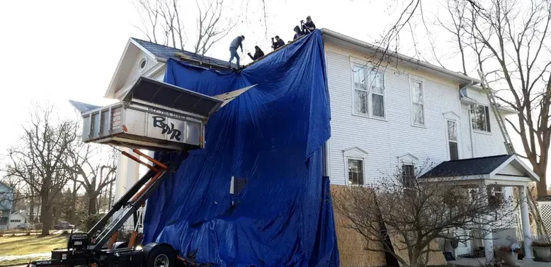 Roofers working on a white house.