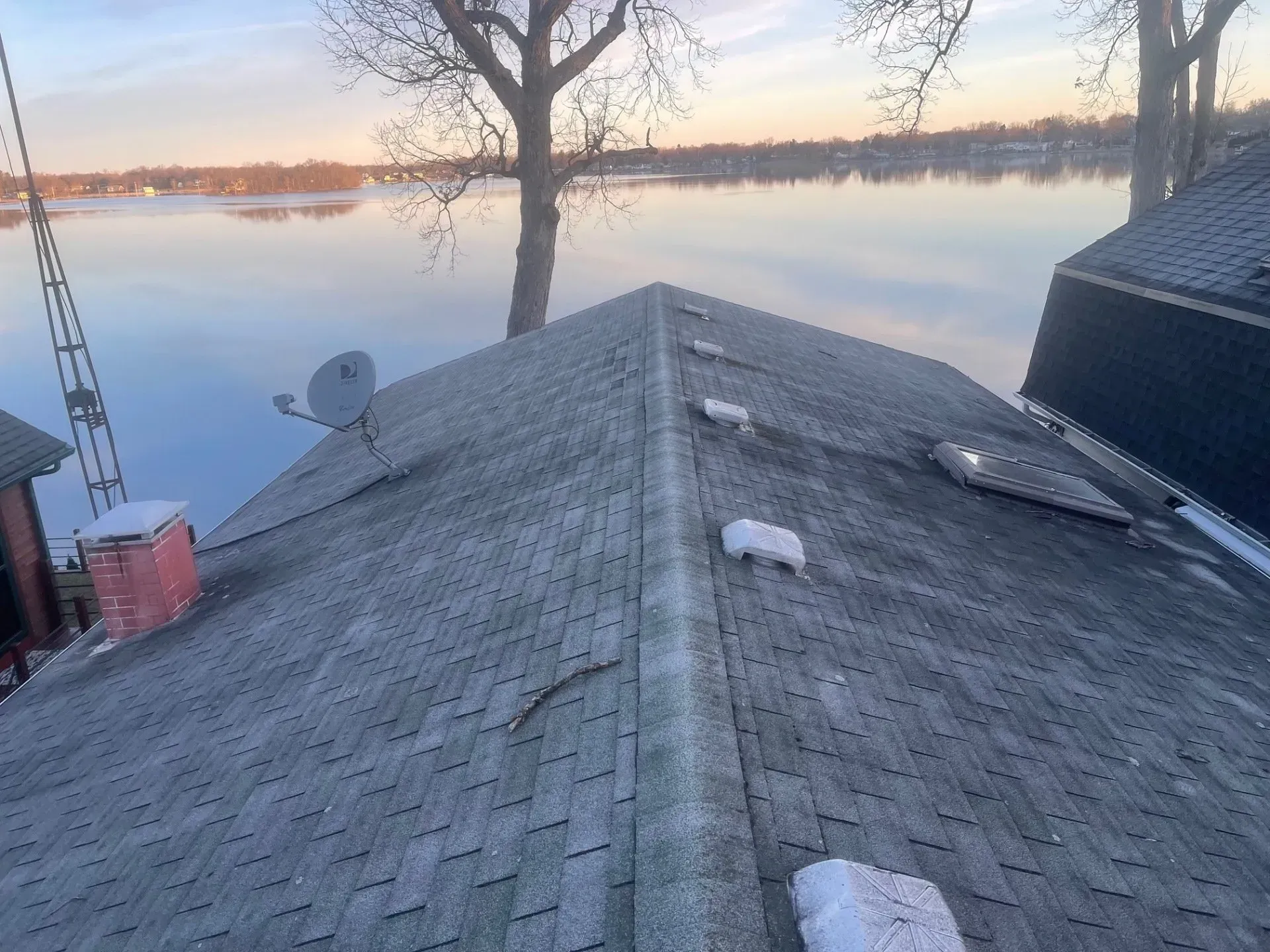 Gray shingle roof overlooking a lake at sunset. 