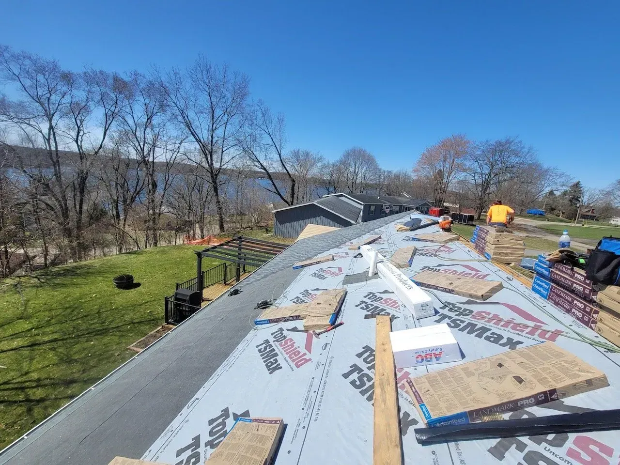 Roof being worked on under a bright blue sky.