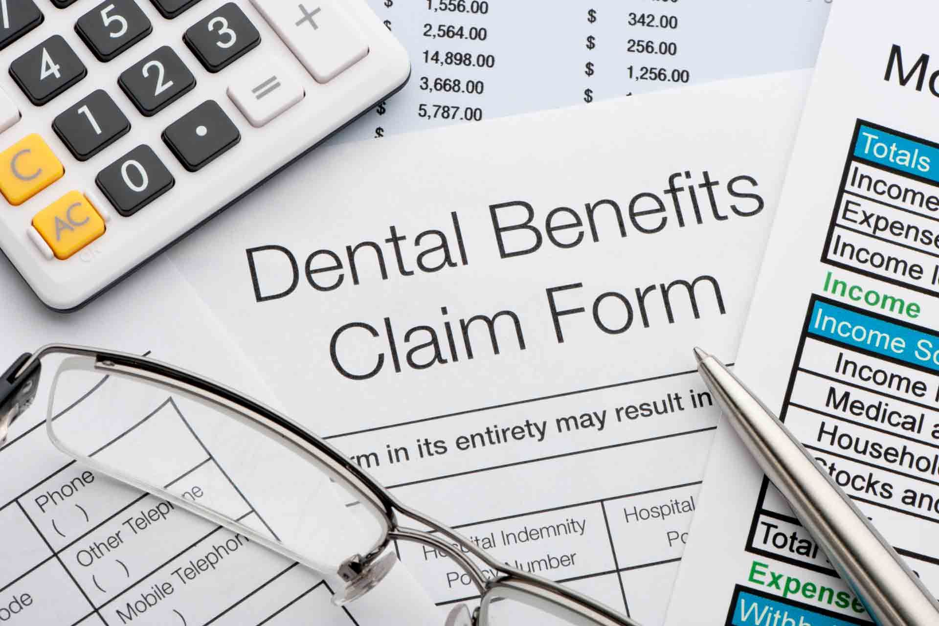 Dental benefits claim form with calculator, glasses, and financial documents.