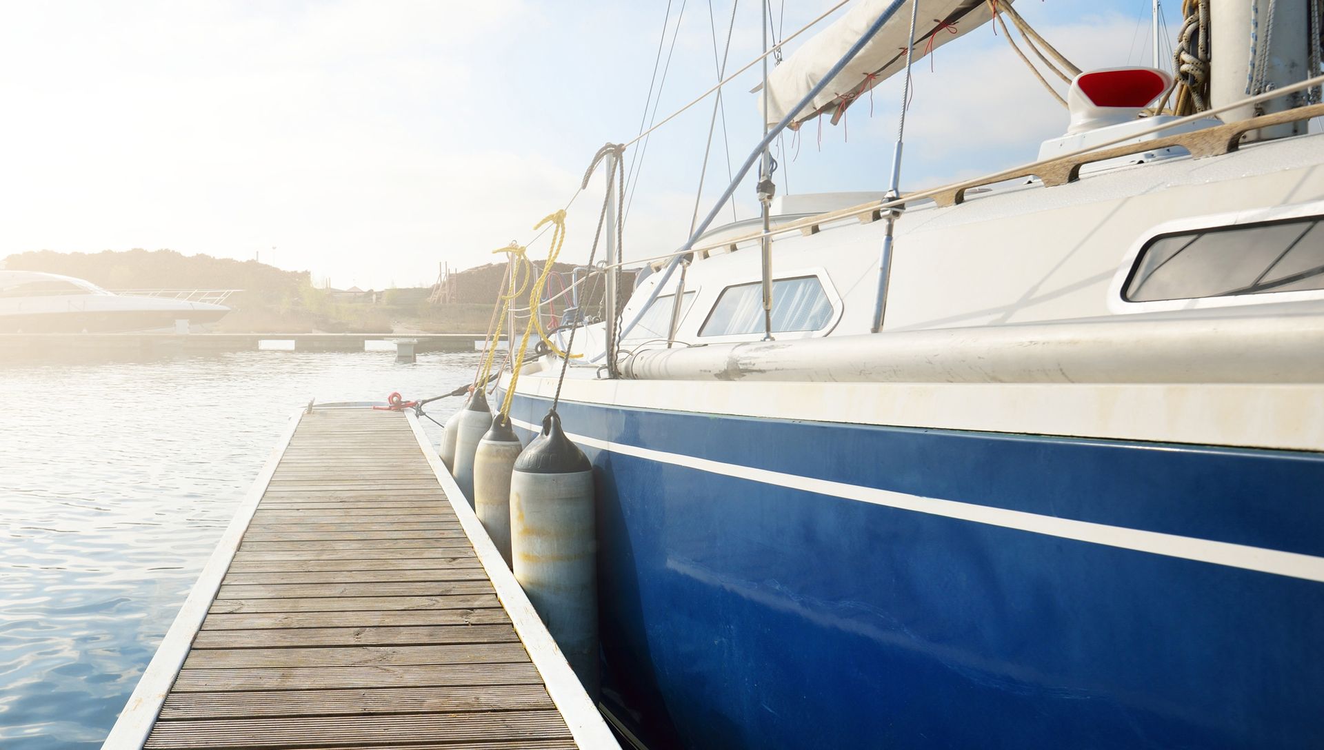 close-up of the side of blue yacht moored to a pier