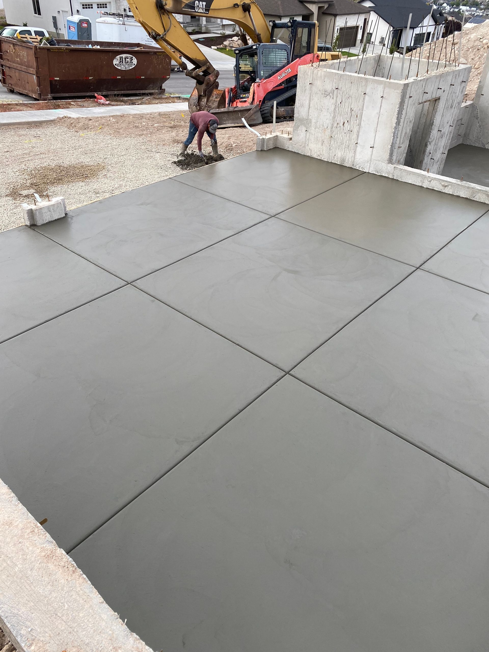 Person smoothing wet concrete slab at construction site.