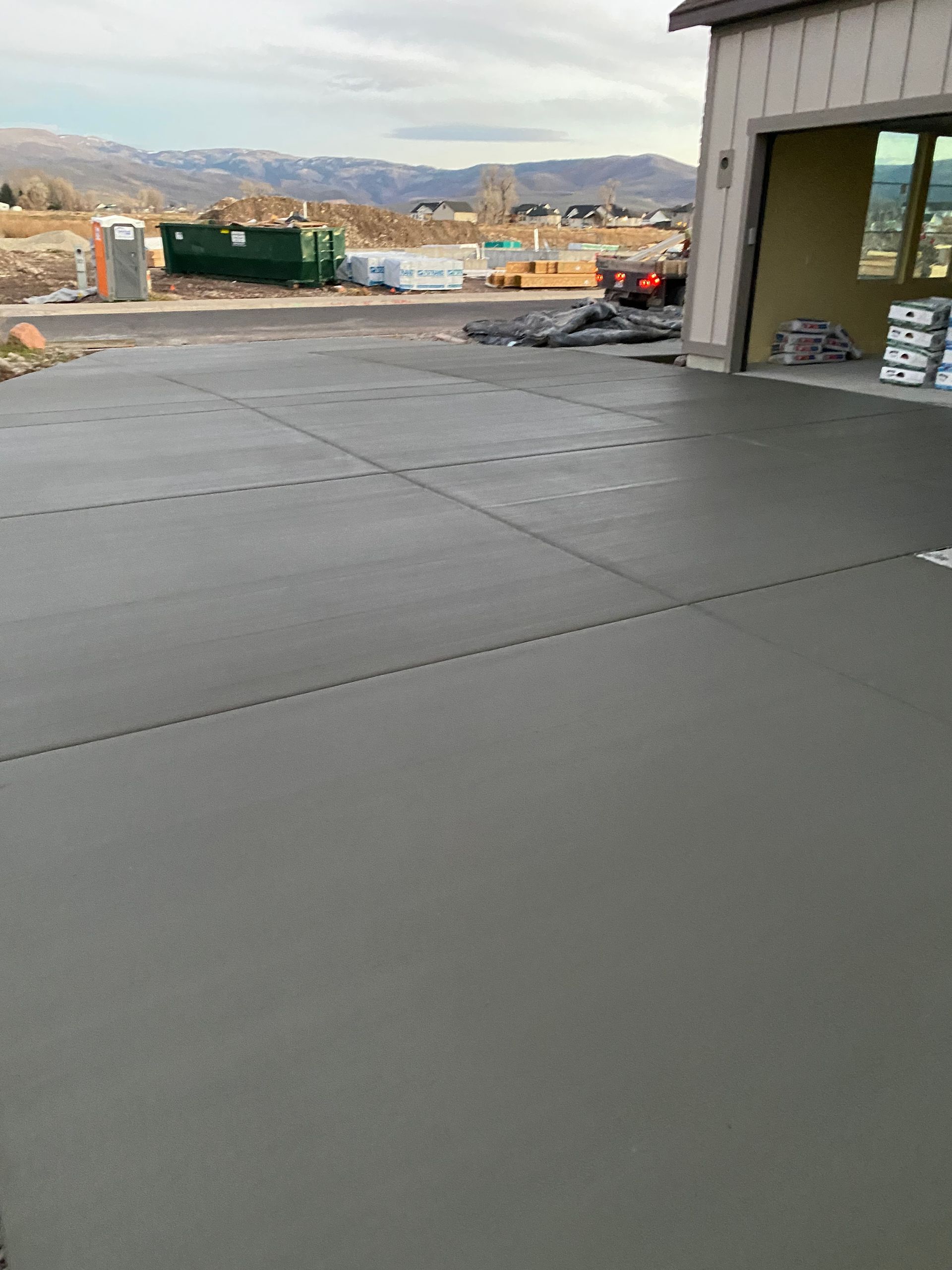 Newly poured concrete driveway with mountain view in the background, next to a garage.