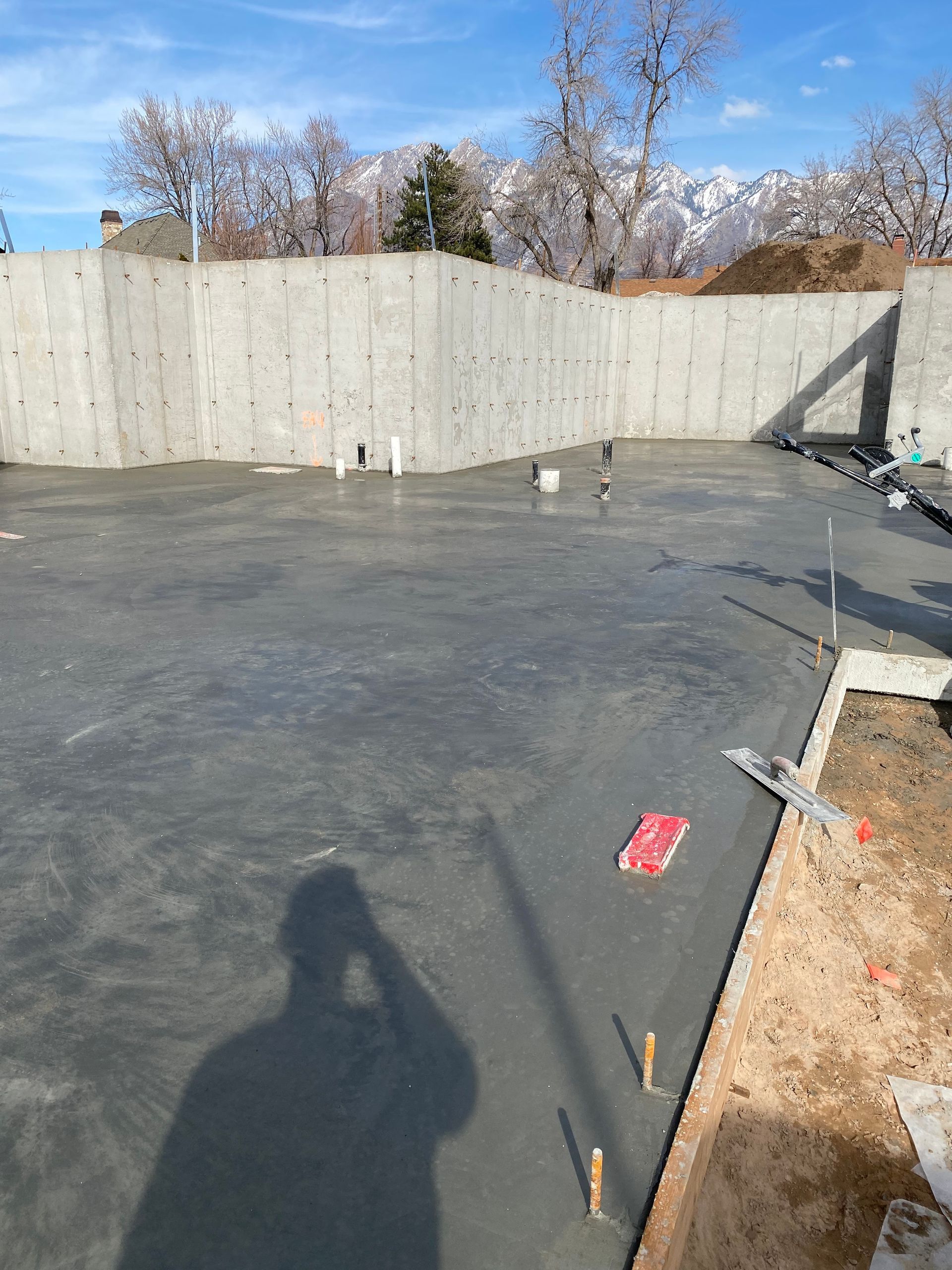 Newly poured concrete slab within concrete walls, with mountains in background.