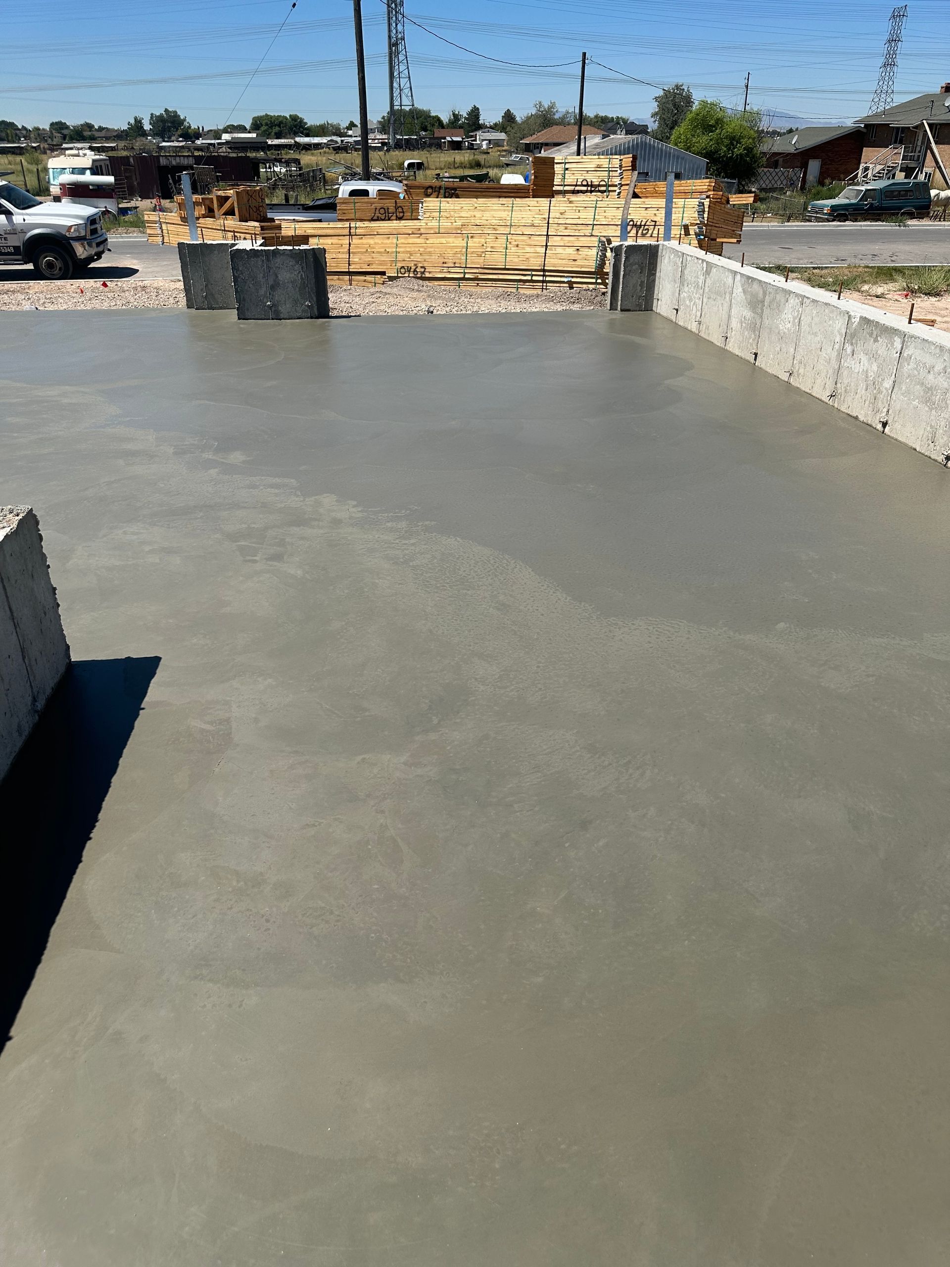 Freshly poured concrete slab with cinder block borders, outdoors on a sunny day.