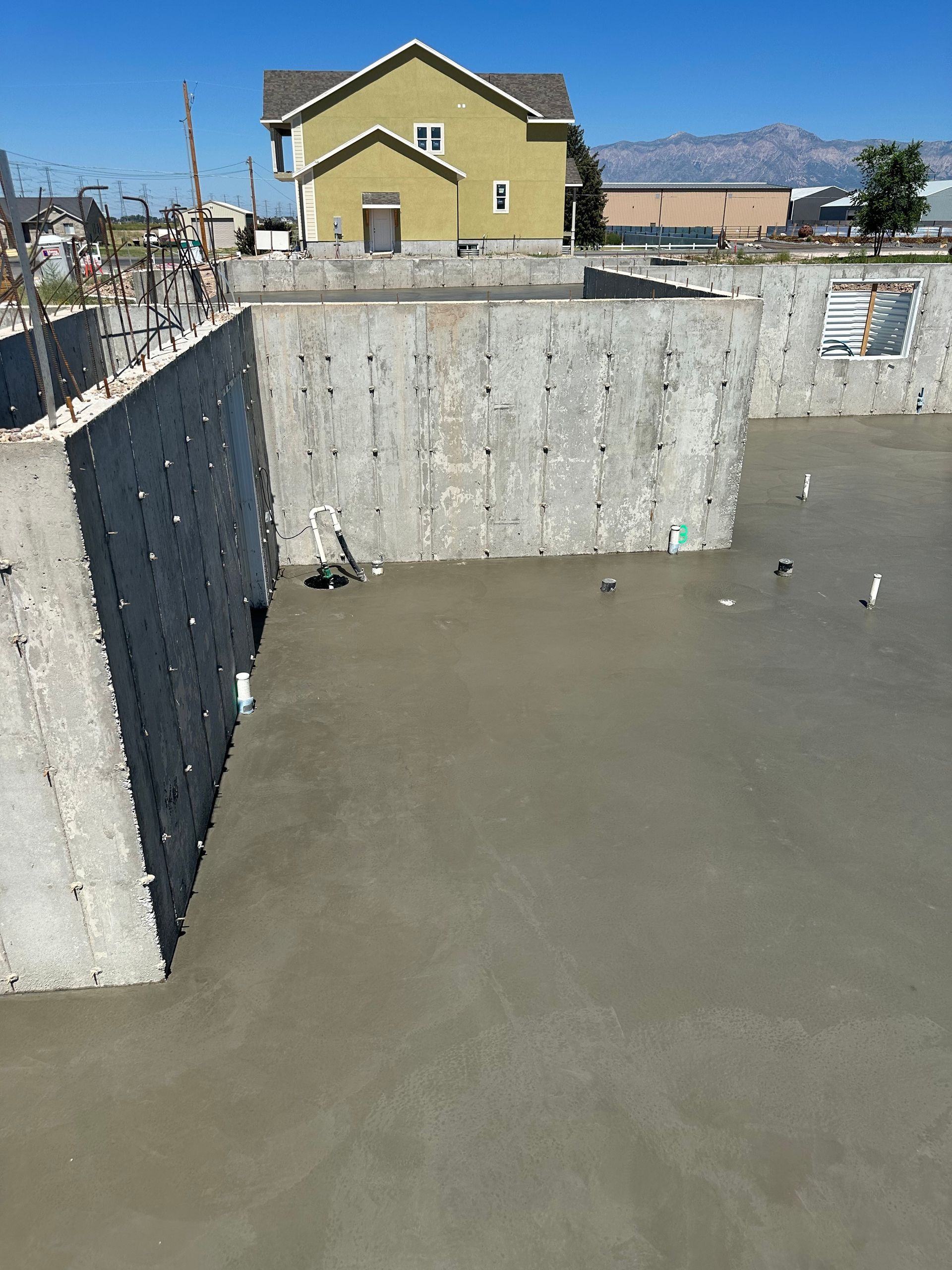 Concrete foundation of a house being built, with a poured concrete floor and gray walls.