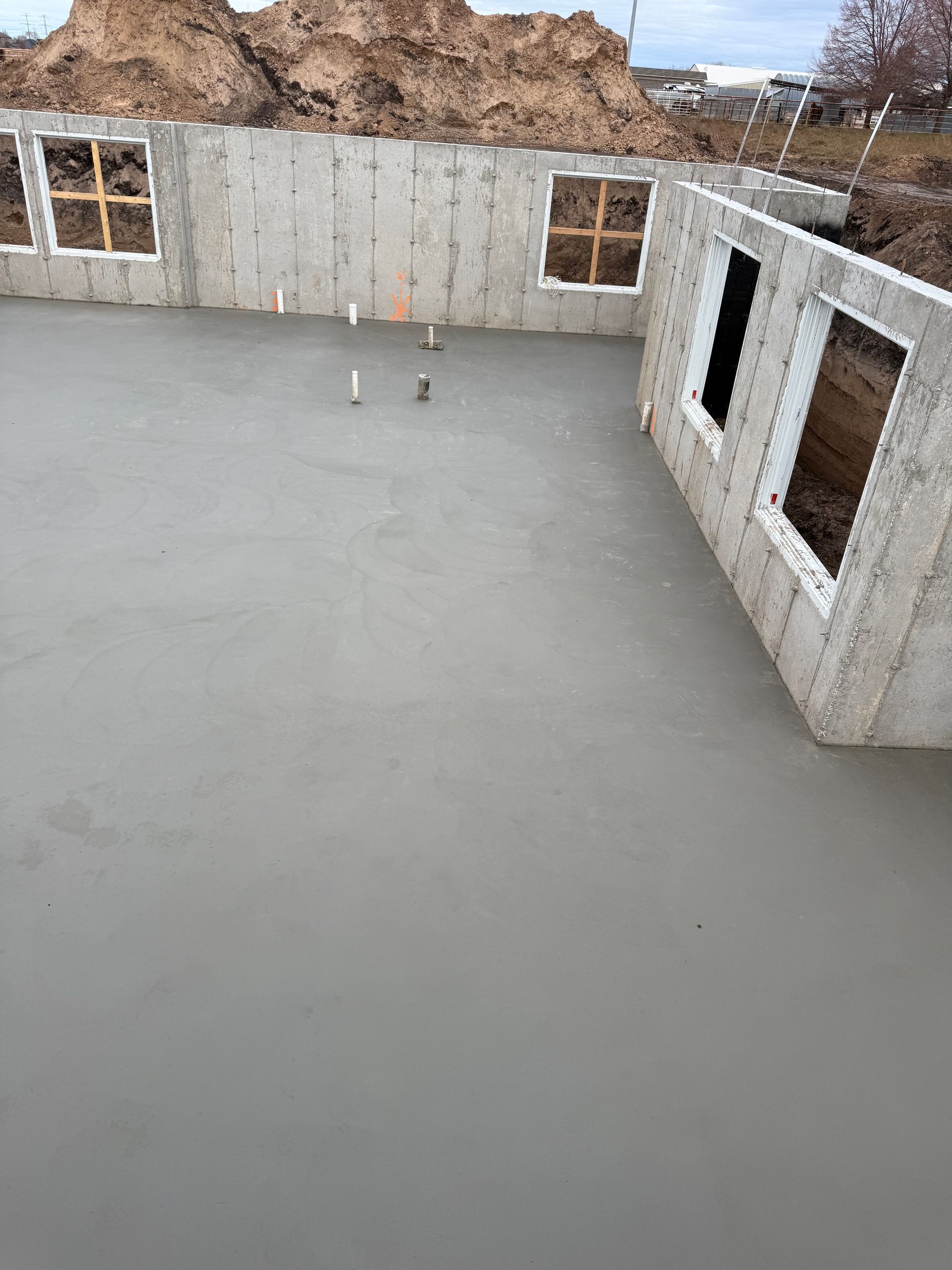 Newly poured concrete foundation with window frames in exterior walls.