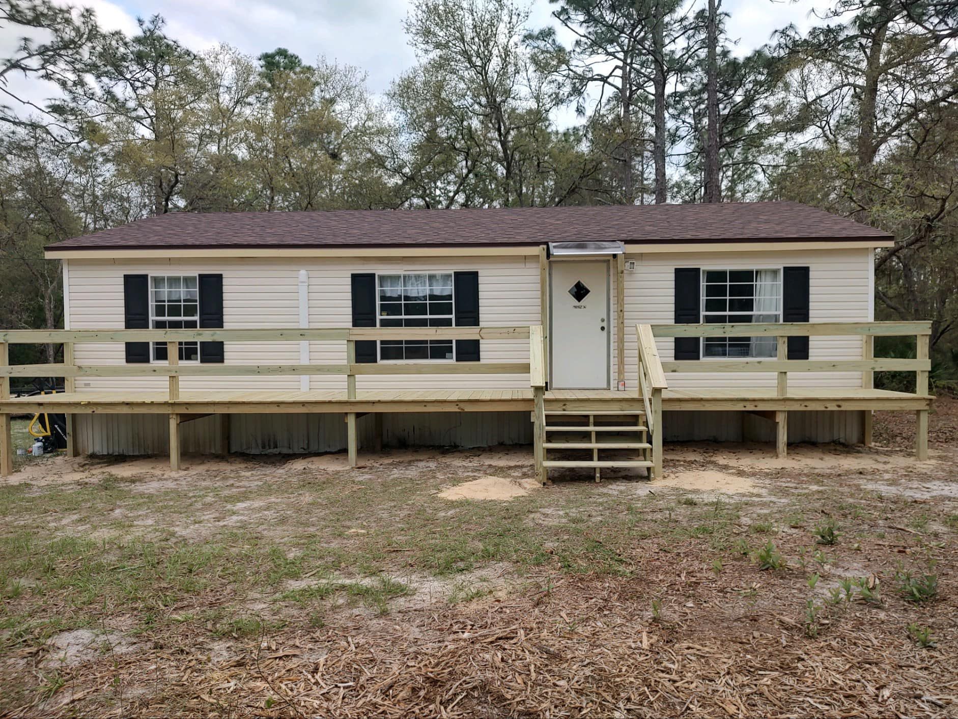 Woman in straw hat smiles, holding wine glass near a lake.