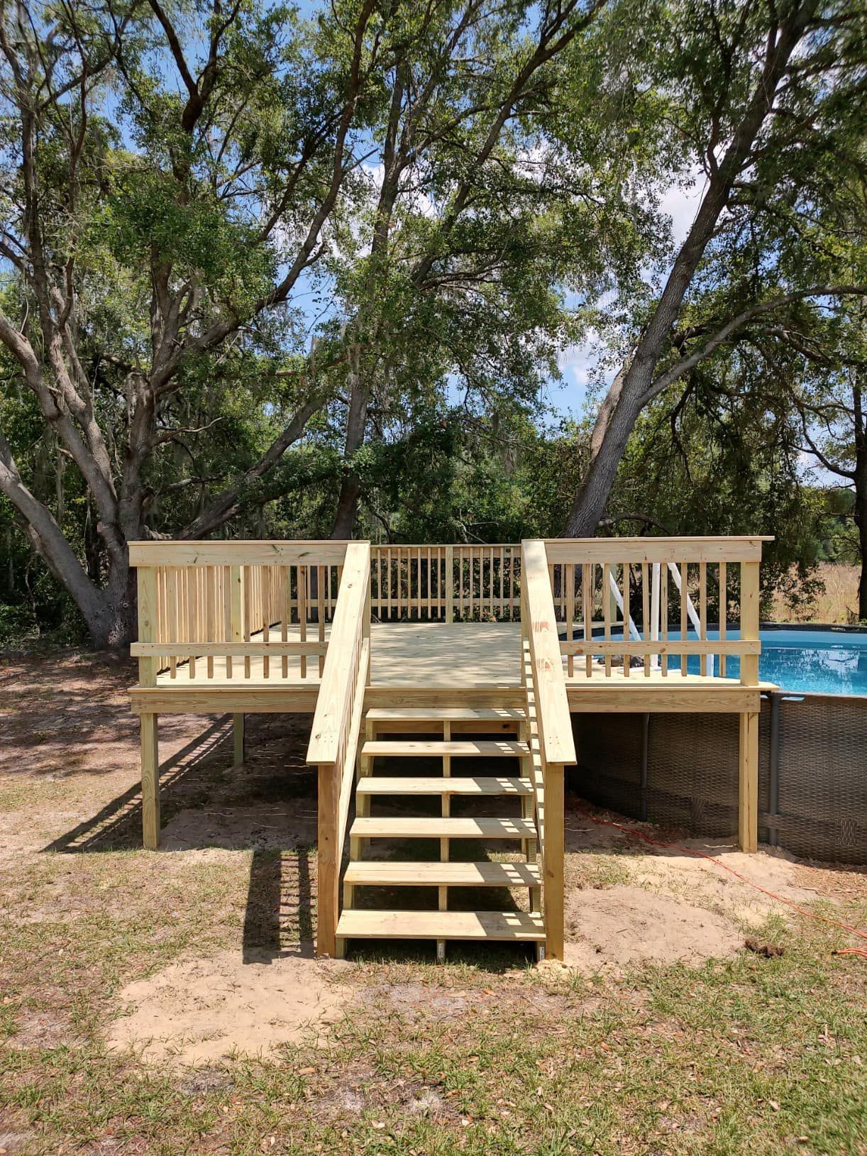 Woman in straw hat smiles, holding wine glass near a lake.