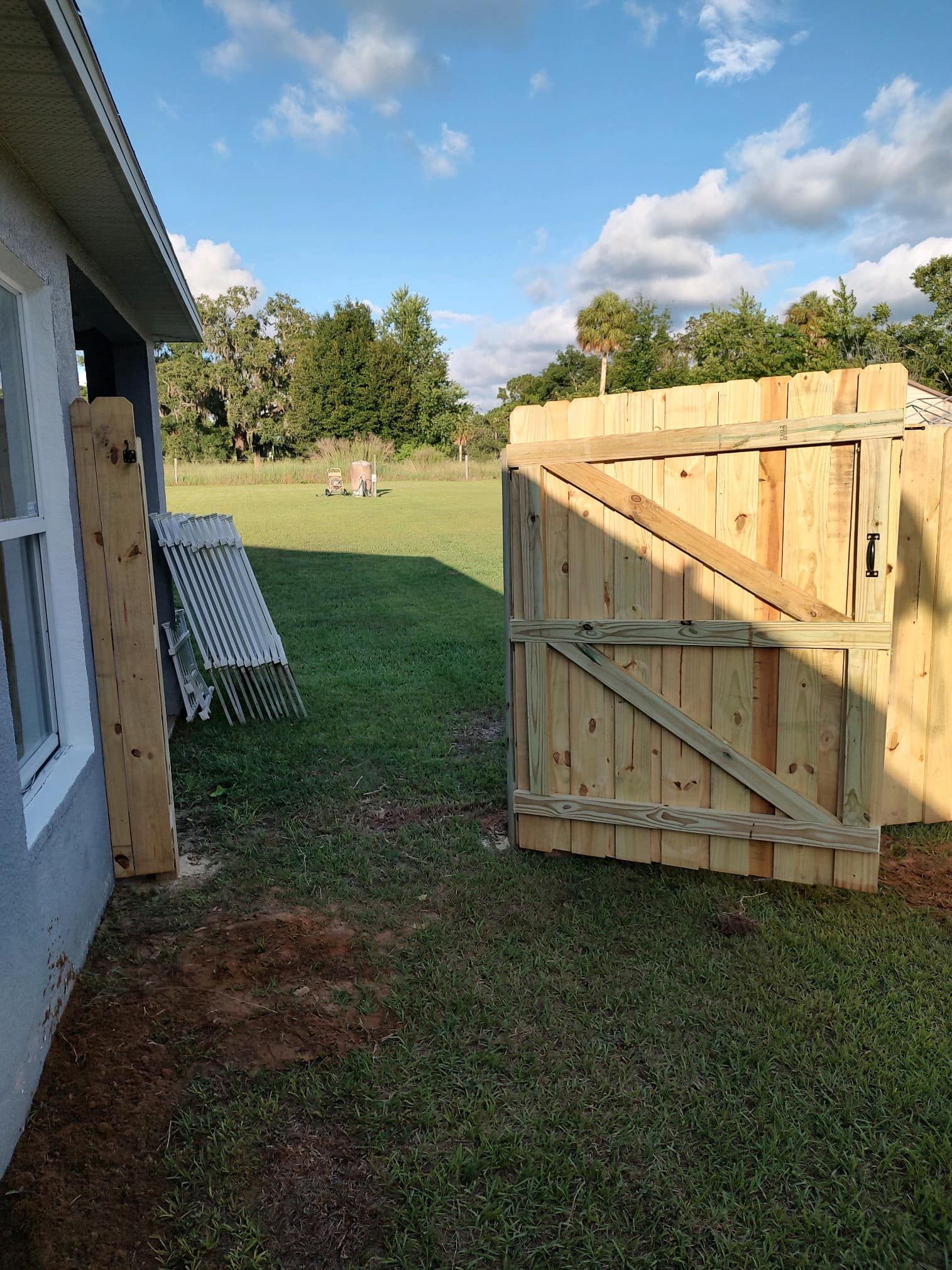 Woman in straw hat smiles, holding wine glass near a lake.