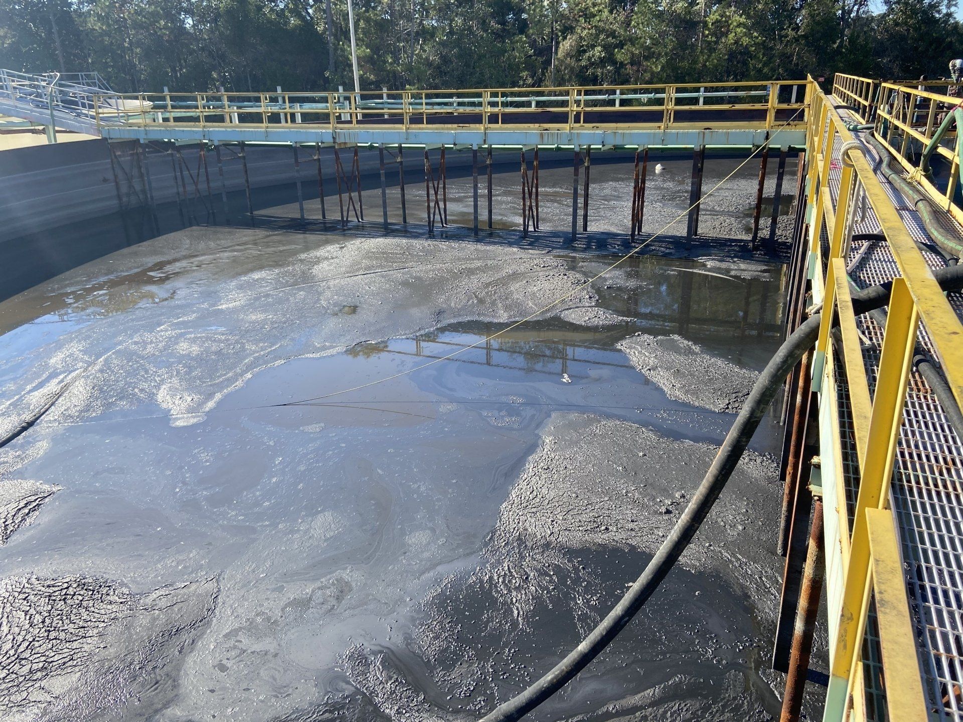 A large body of water with a yellow railing and a hose attached to it