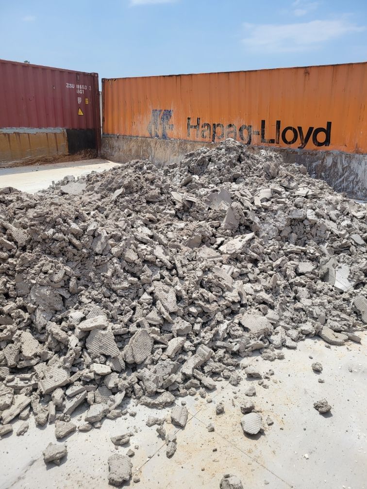 A pile of rocks in front of a shipping container that says hong lloyd