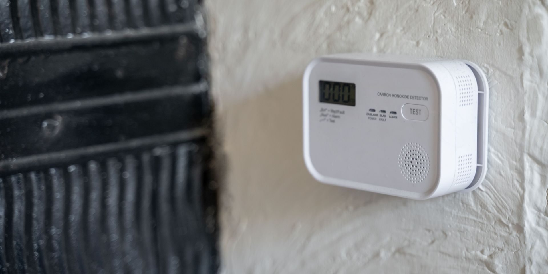 A white smoke detector is hanging on a white wall.