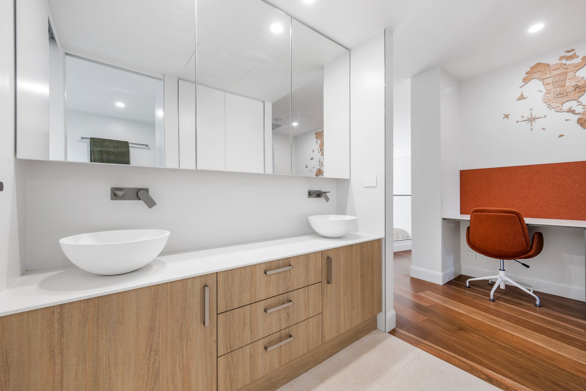 Bathroom with wood vanity, white sinks, large mirror, and adjacent home office with desk and orange chair. — Kitchens Factory Direct in Port Macquarie, NSW
