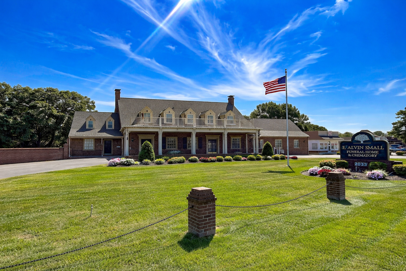 a large house is sitting on the shore of a lake surrounded by trees .