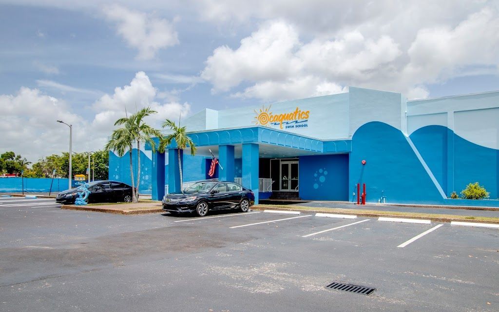 A blue and white building with cars parked in front of it with a swim school