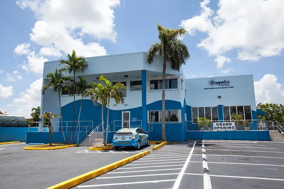 A blue car is parked in front of a blue building for a swim school