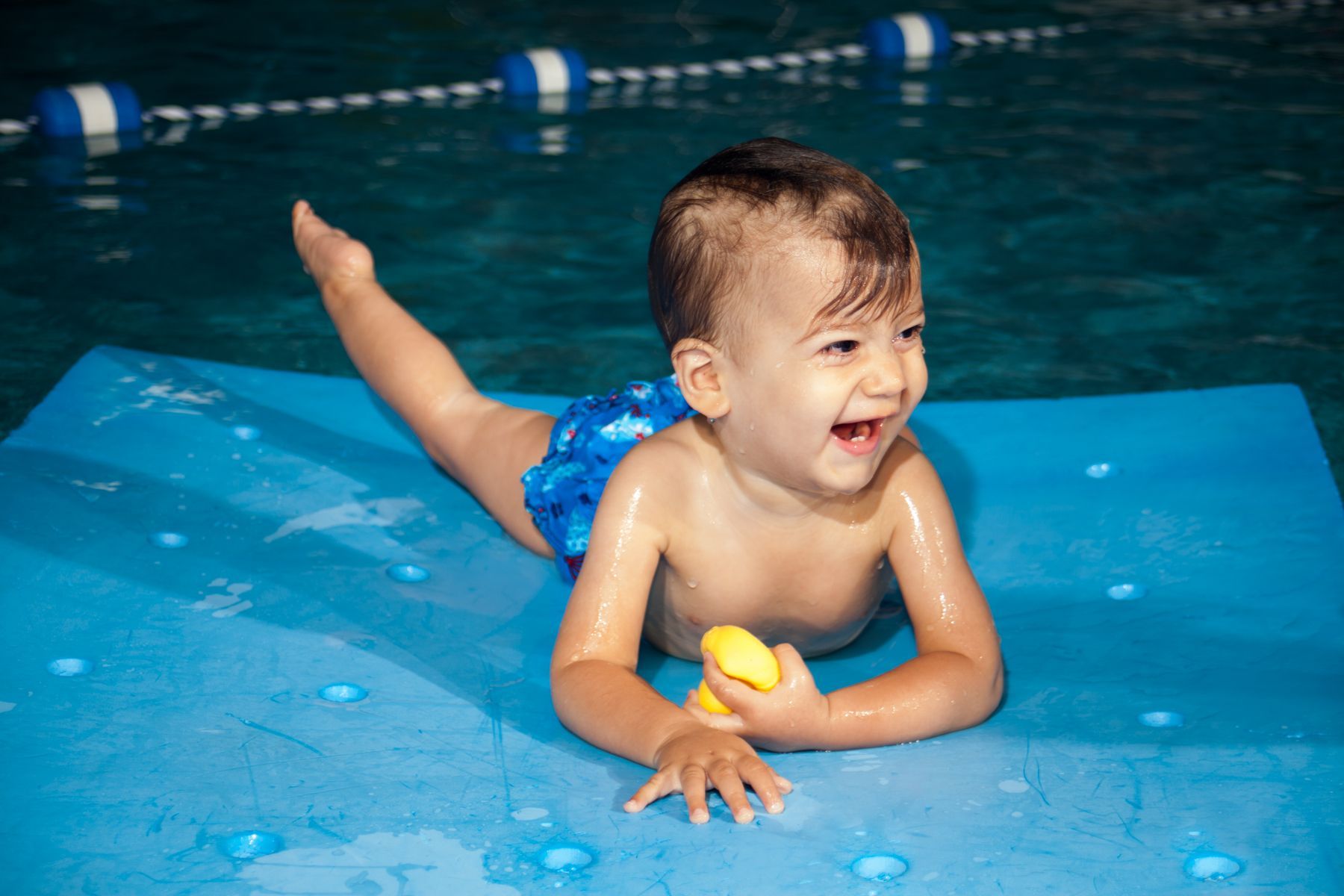 un bebé está acostado sobre una alfombra azul en una piscina.