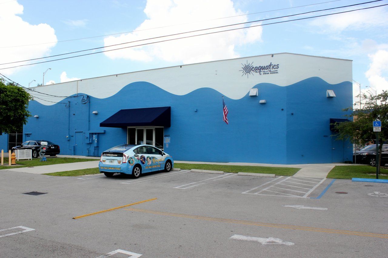 A blue and white building with a car parked in front of it for a swim school