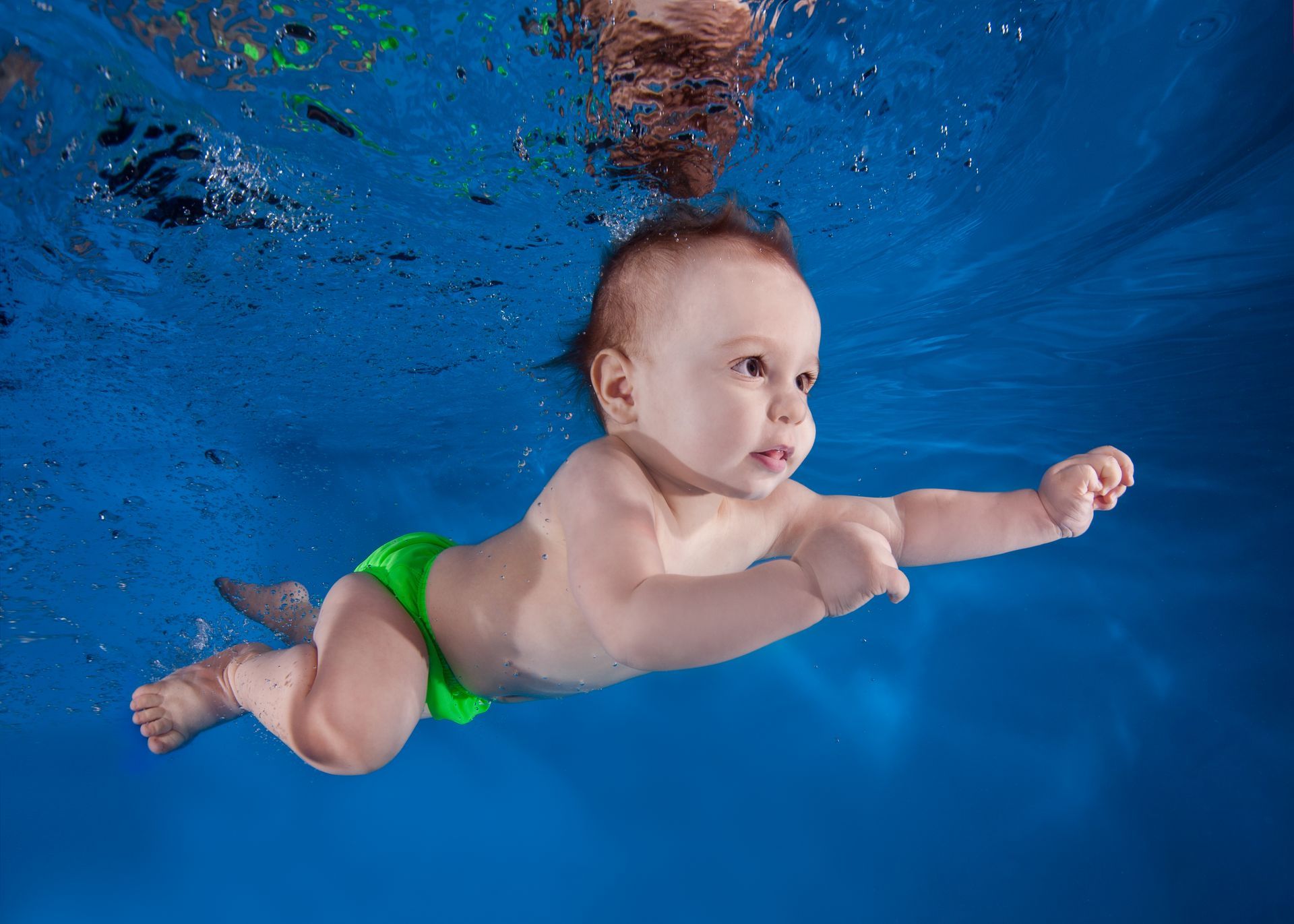 A photo of a young baby swimming underwater.