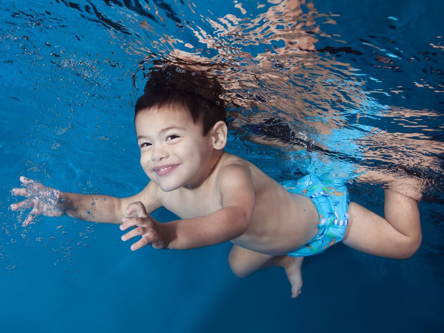 Un niño nada bajo el agua en una piscina en clases de natación en Ocaquatics