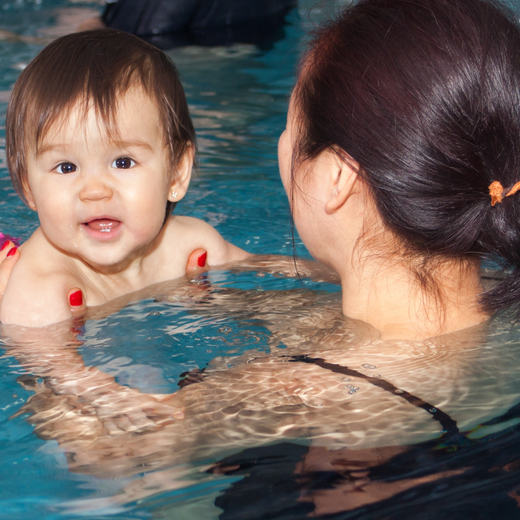a woman is holding a baby in a swimming pool for swim lessons