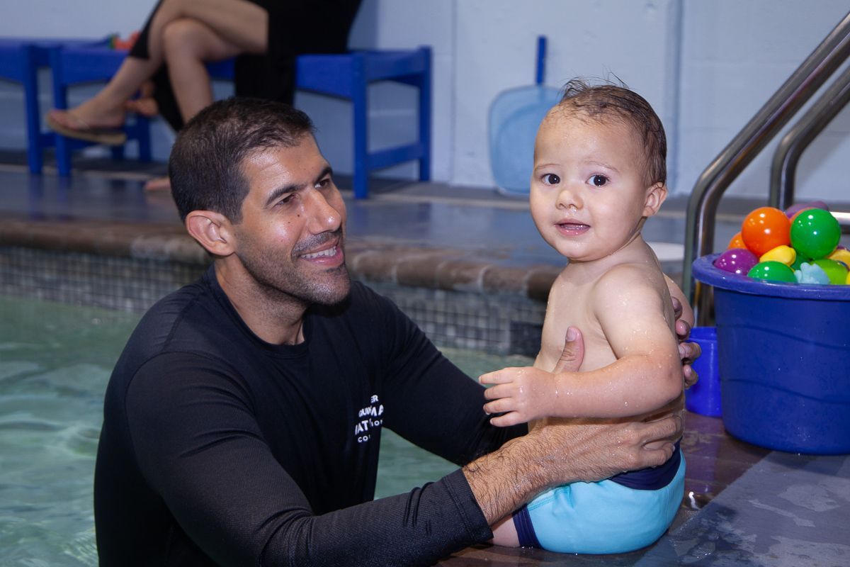 Photo of a swimming instructor in a pool holding a toddler 