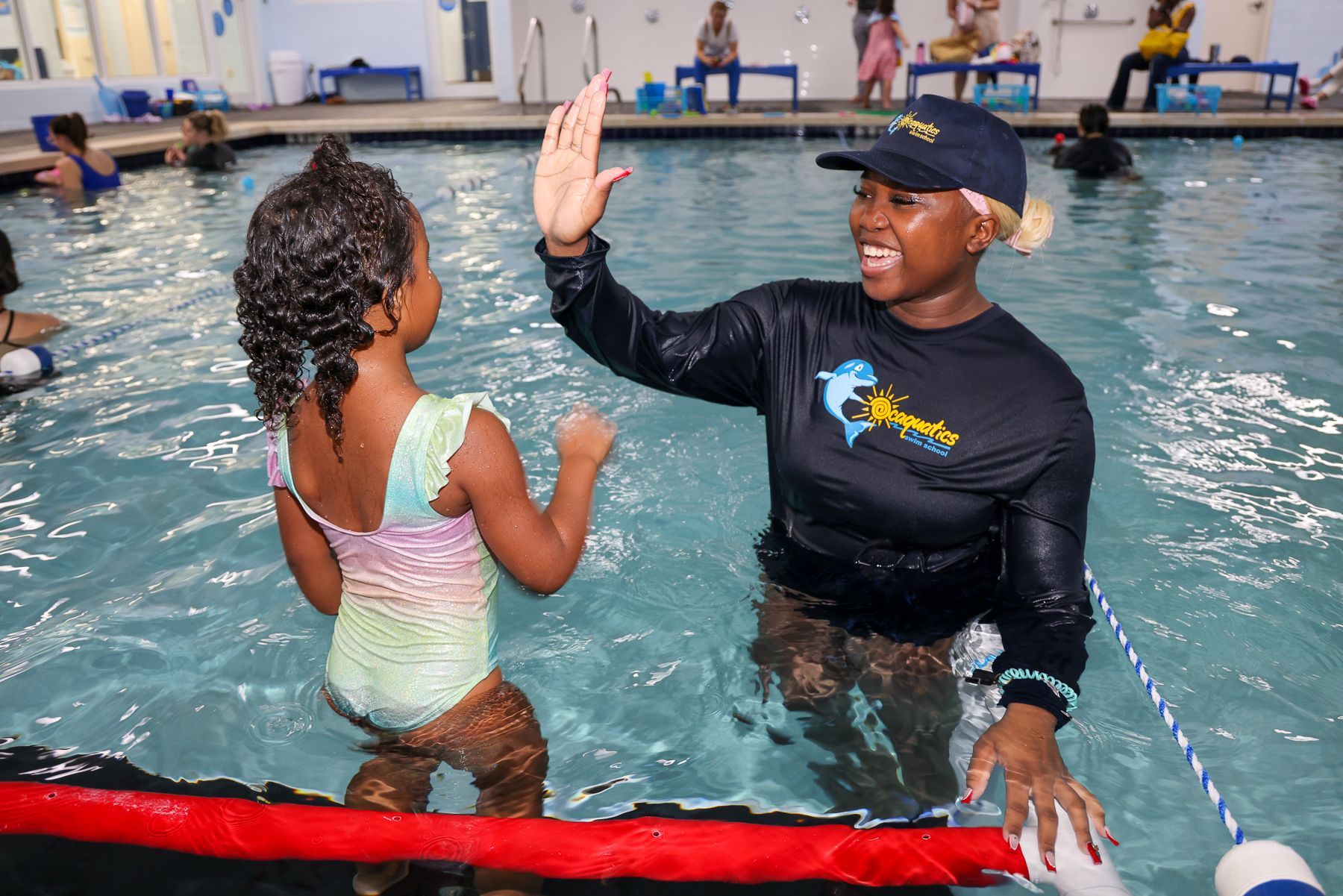 Photo of a kid high-fiving their swimming instructor