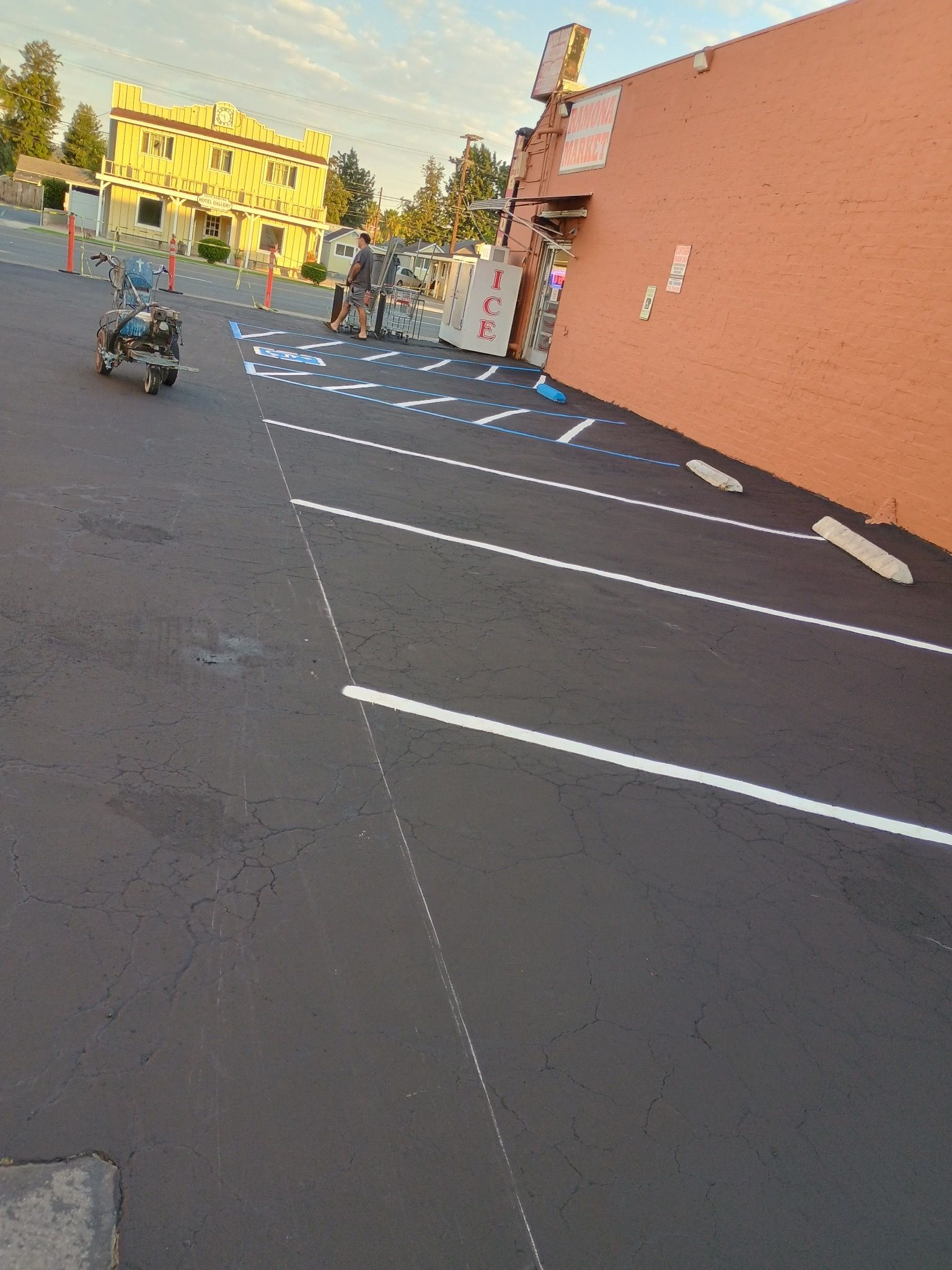 A person is riding a scooter in a parking lot in front of a building.