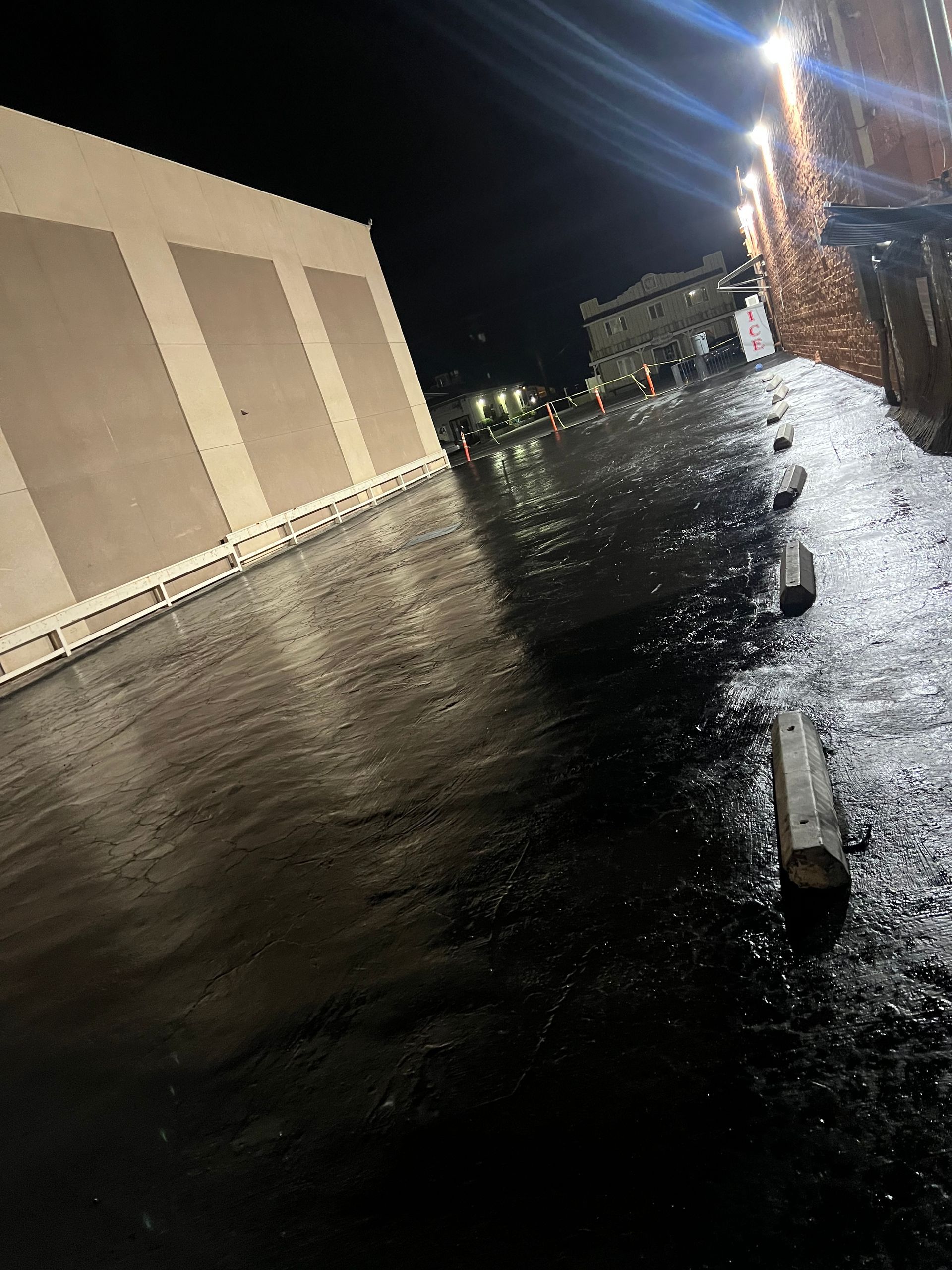A flooded parking lot with a building in the background at night.