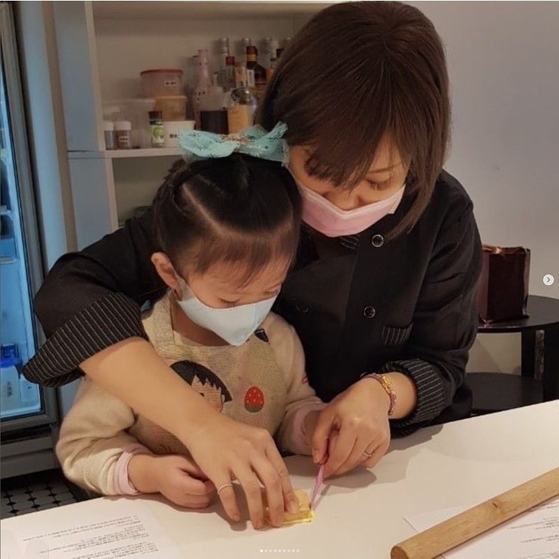 一名戴著口罩的小女孩正在接受一名婦女的幫助