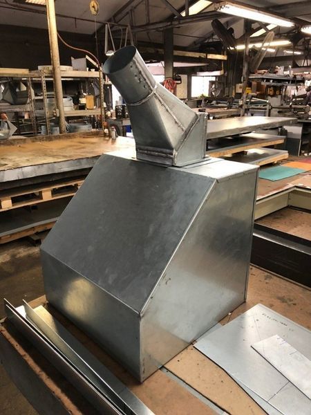 A metal pipe is sitting on a wooden table in a factory