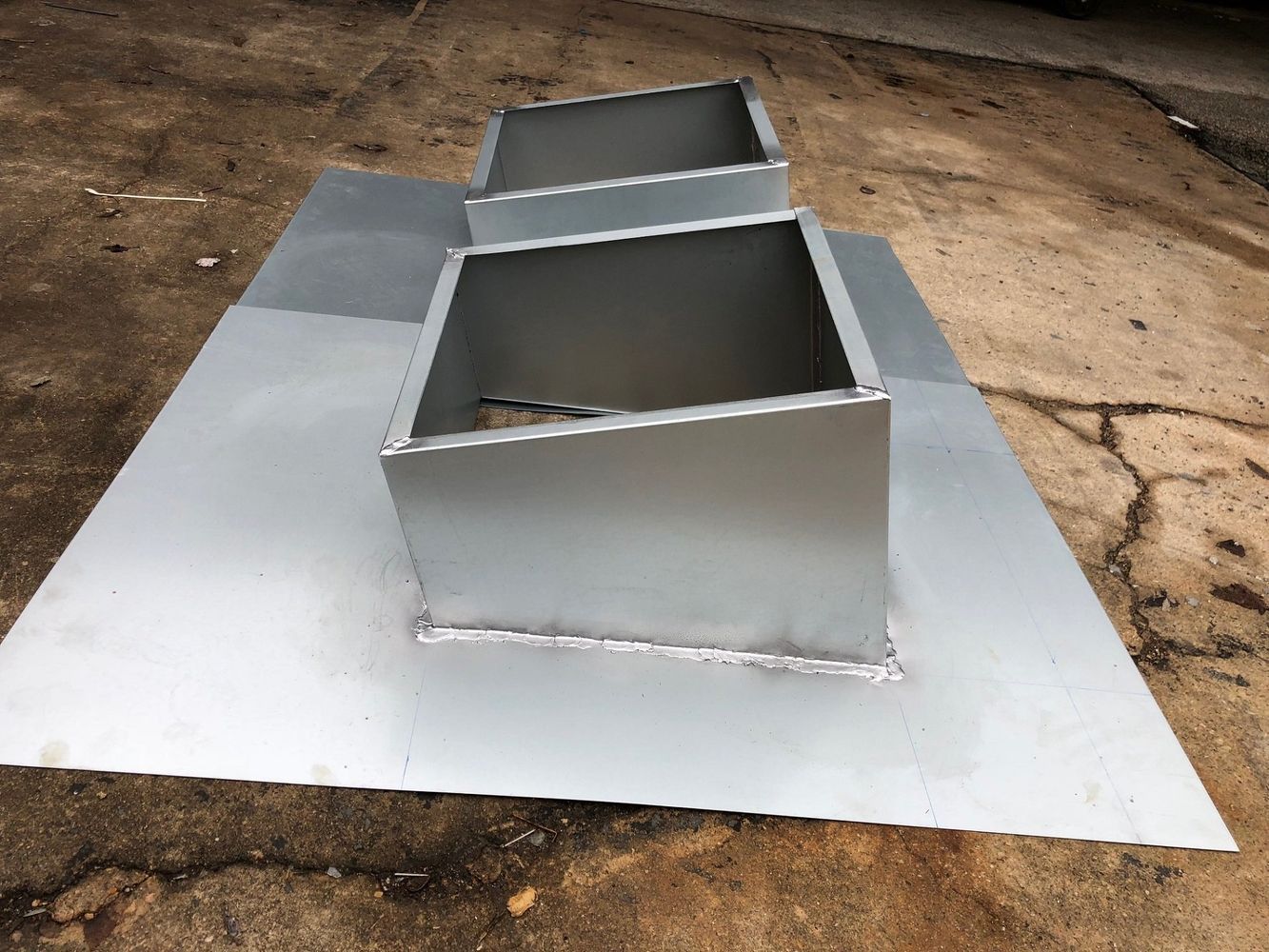 Three metal boxes are sitting on top of a piece of metal.