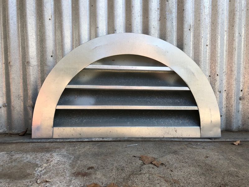 A metal shelf is sitting in front of a corrugated metal wall.