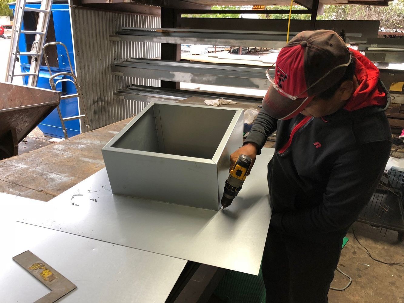 A man is working on a piece of metal with a drill.