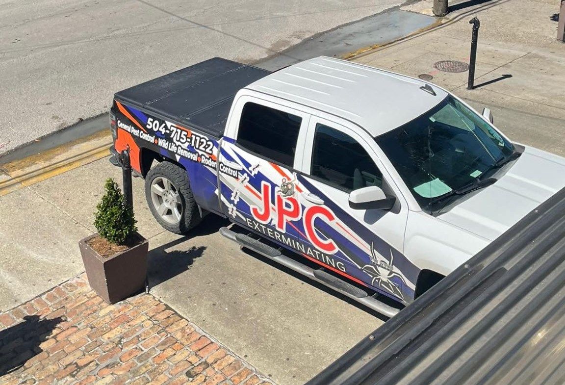 Two men in protective suits are spraying boxes in a warehouse.