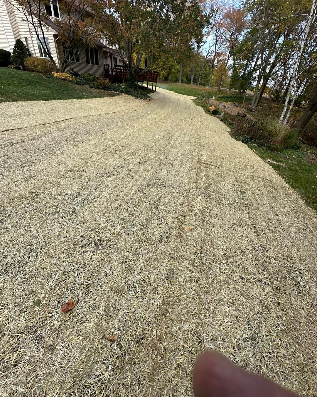 Gravel pathway alongside a lawn, leading to a house. Brown and tan colors dominate the scene.