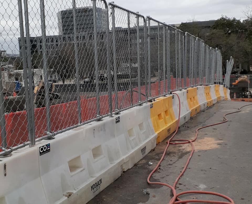 A chain link fence on water filles barriers