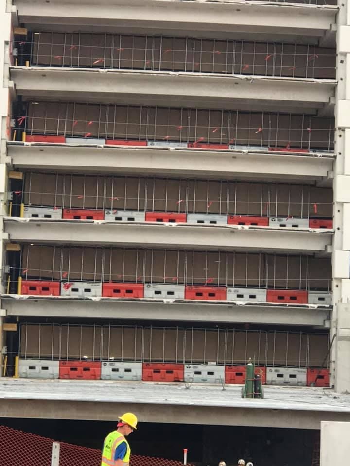 A construction worker is standing on the roof of a building under construction.