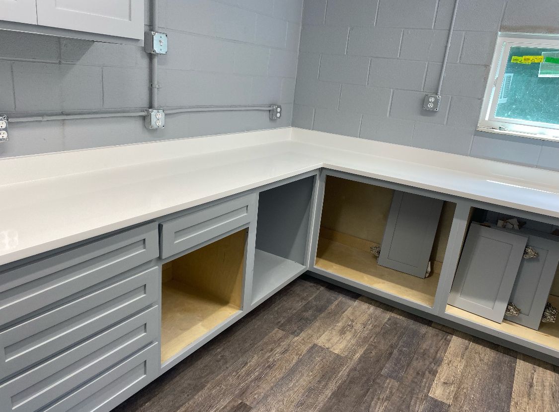 A kitchen with gray cabinets and a white counter top.