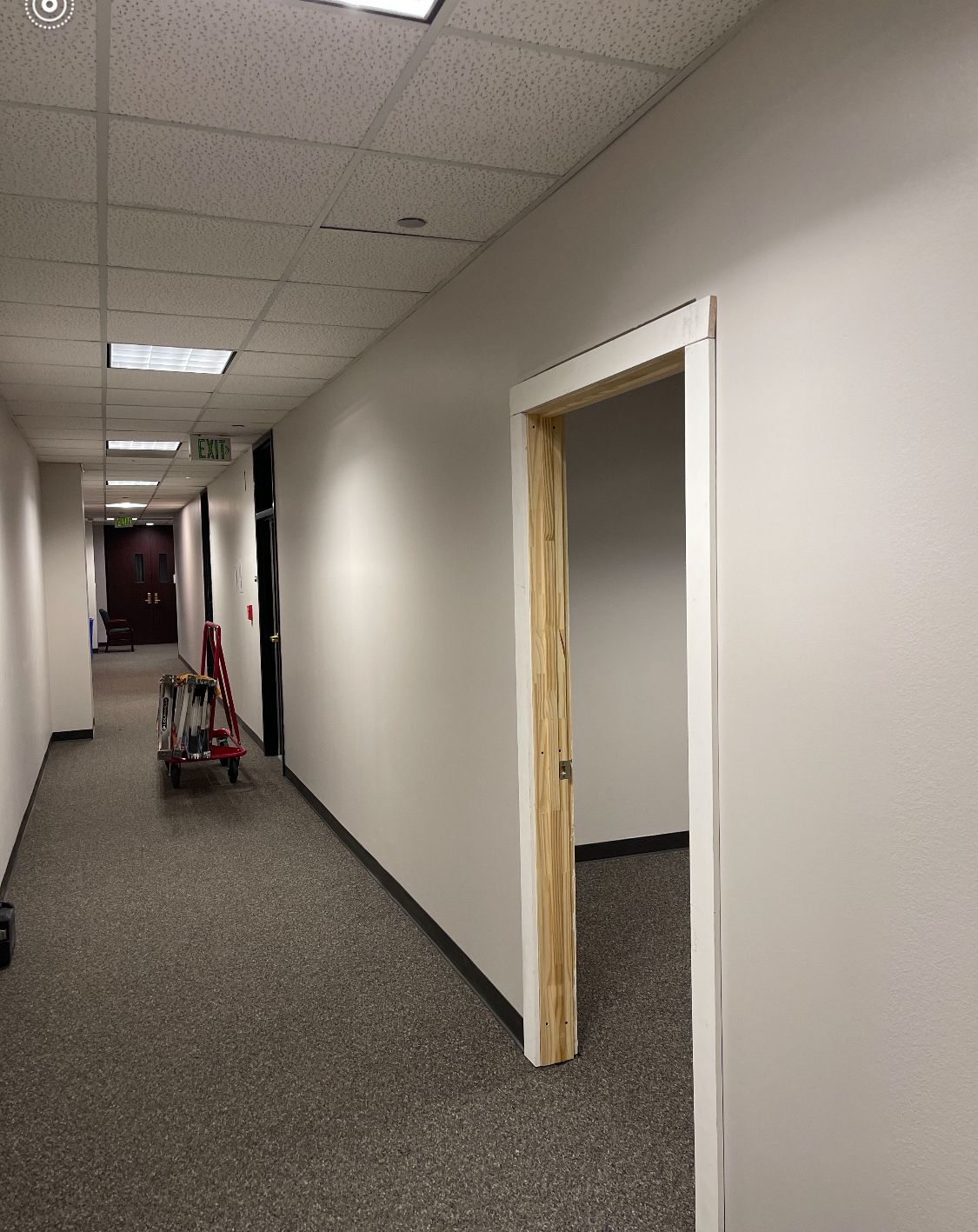 A long hallway with a red cart in the middle of it.