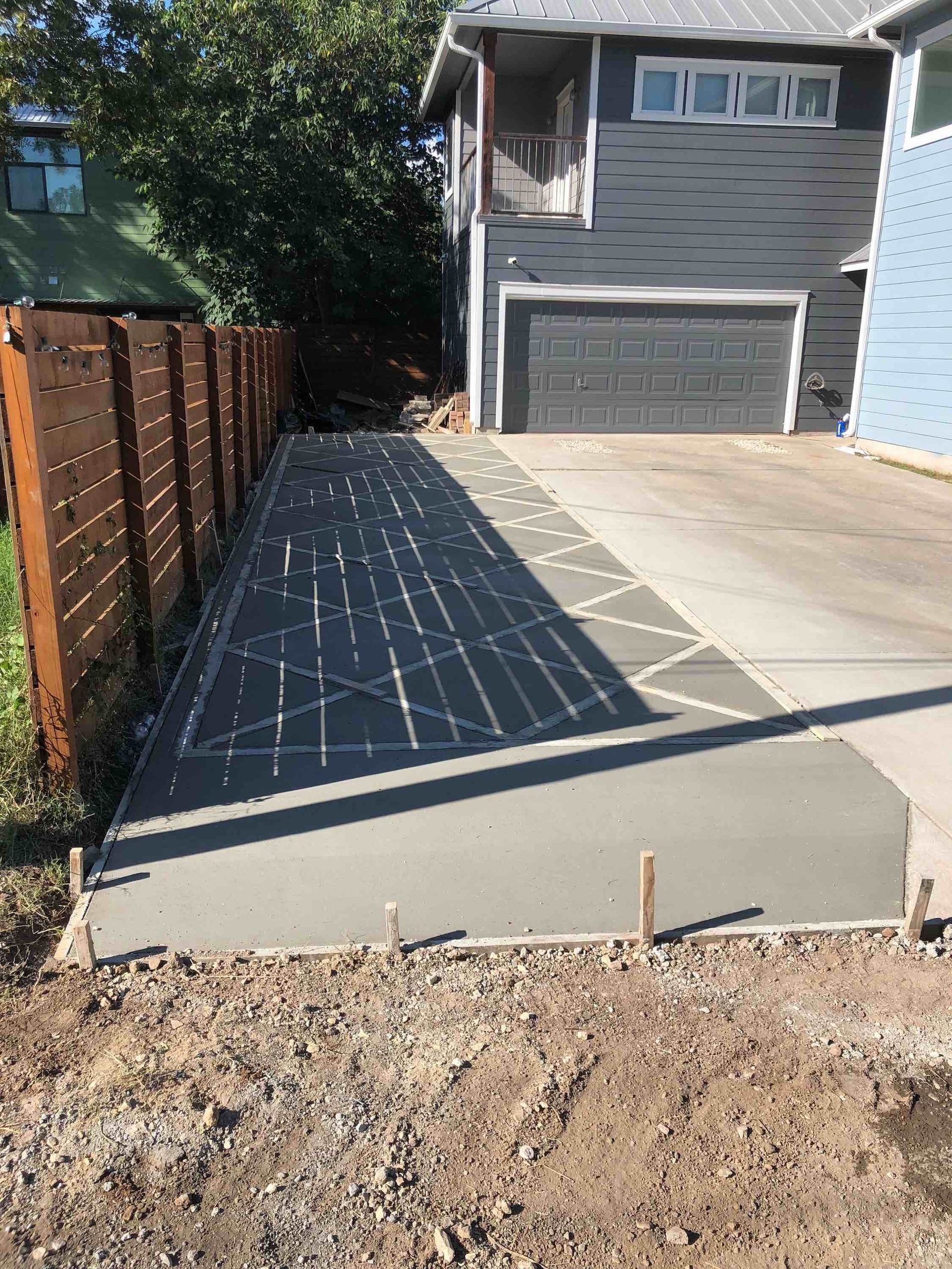 A concrete walkway is being built in front of a house.